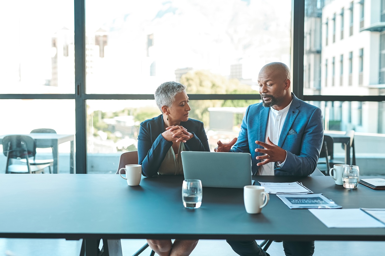 Affaires, présentation et homme sur un ordinateur portable lors d’une conférence d’entreprise ou d’une collaboration dans un bureau avec une femme au travail.